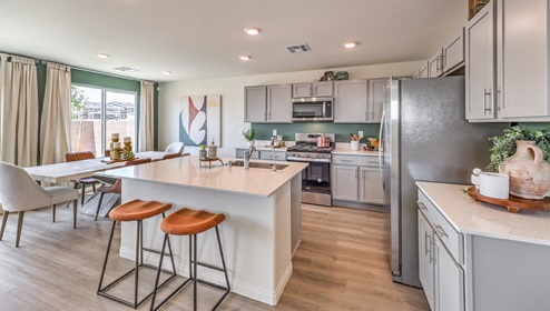 Our 1865 model kitchen in the Heartland Bay Community with grey shaker style cabinets, granite slab countertops, a kitchen island, large pantry, and Whirlpool Stainless Steel appliances.
