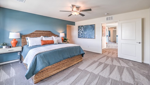 The Bedroom Five in our Heartland Falls 3000 model with carpet flooring, ceiling fan with a light kit, and large windows.