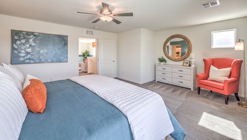 The Bedroom One Suite in our Heartland Falls 3000 model with carpet flooring, ceiling fan with a light kit, and large windows.