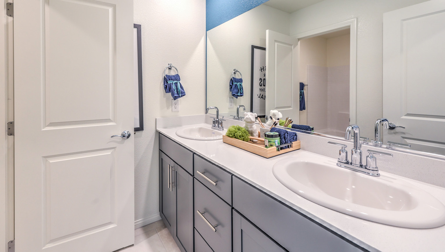 Bathroom Three in our Heartland Falls 2600 model with Granite countertops at the double Bath Vanity, a shower, mirror, and white cabinets.