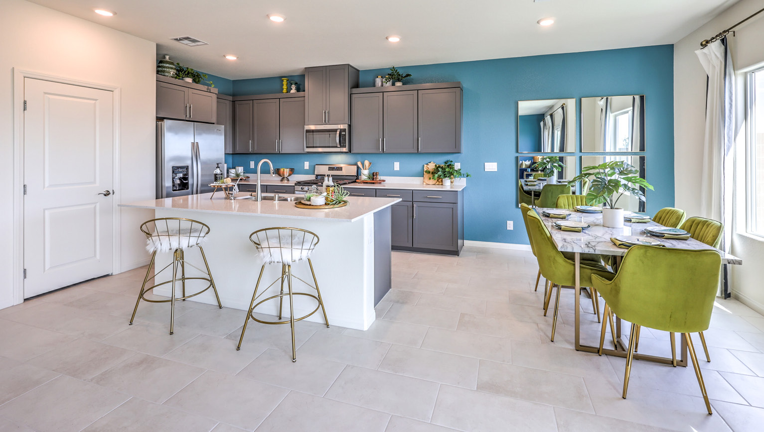 Our 2660 model kitchen in the Heartland Falls Community with grey shaker style cabinets, Granite Slab countertops, a kitchen island, and Whirlpool Stainless Steel appliances.