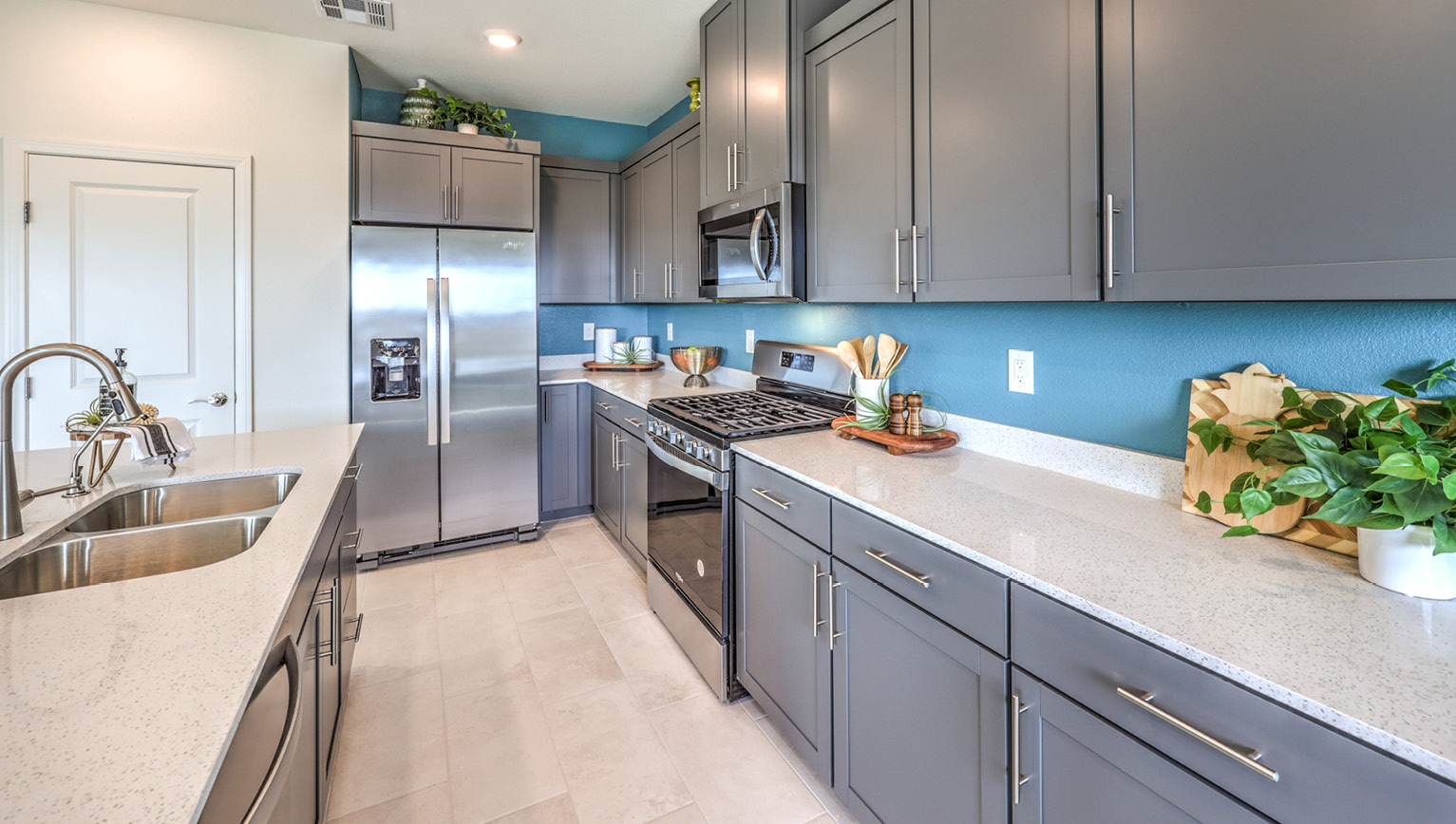 Our 2660 model kitchen in the Heartland Falls Community with grey shaker style cabinets, Granite Slab countertops, a kitchen island, and Whirlpool Stainless Steel appliances.