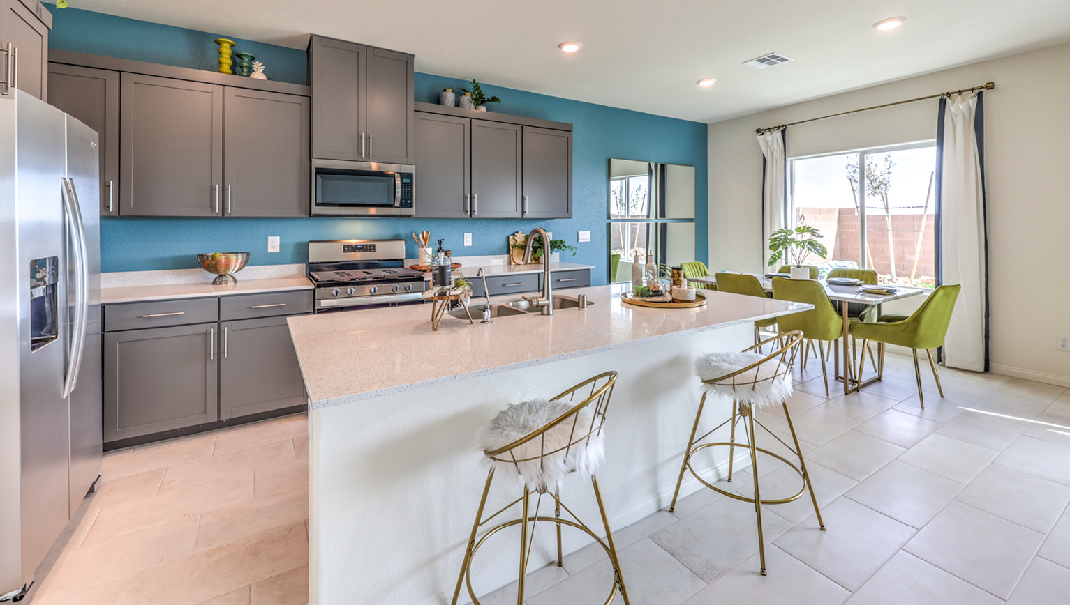 Our 2660 model kitchen in the Heartland Falls Community with grey shaker style cabinets, Granite Slab countertops, a kitchen island, and Whirlpool Stainless Steel appliances.