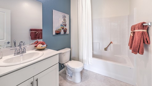 Bathroom Three in our Heartland Falls 3000 model with Granite countertops at the double Bath Vanity, a walk-in shower, mirror, and white cabinets.