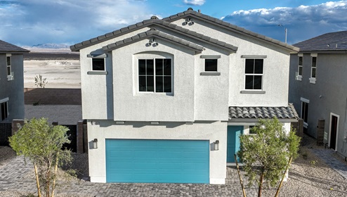 Our 2436 model home in the Heartland Falls community with white and blue exterior paint schemes, a flat tile roof, 2-car garage, front yard landscaping, and paver walkways.