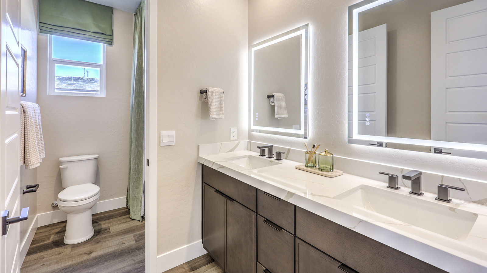 Bathroom Three in our Heartland Summit 4418 model with granite countertops at the double Bath Vanity, a walk-in shower, mirror, and brown cabinets.
