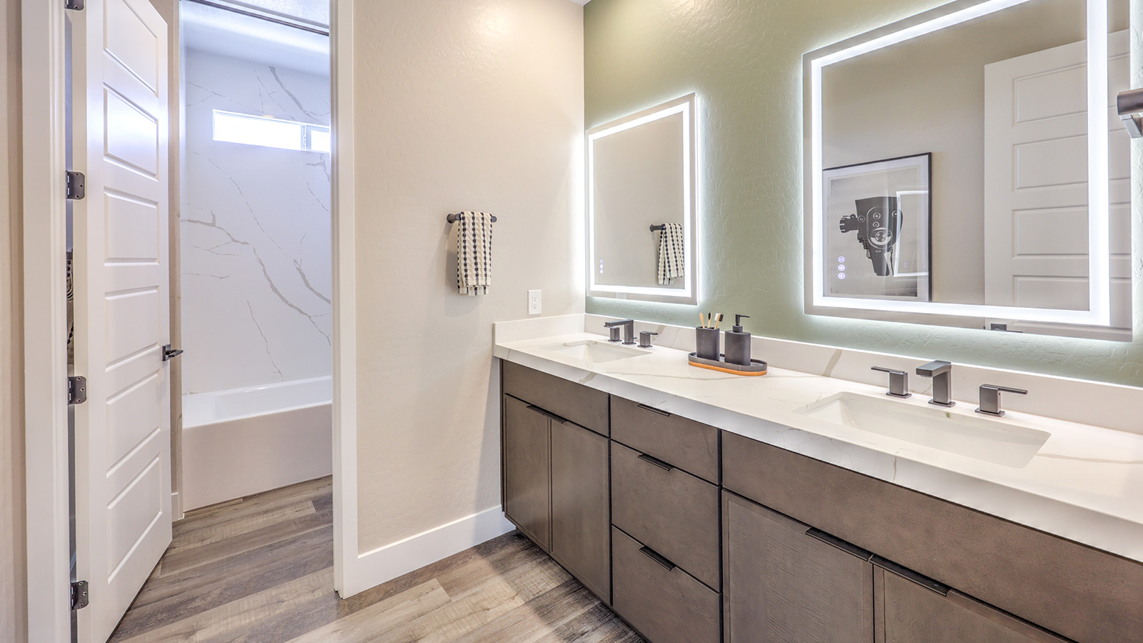 Bathroom Two in our Heartland Summit 4418 model with granite countertops at the double Bath Vanity, a walk-in shower, mirror, and brown cabinets.