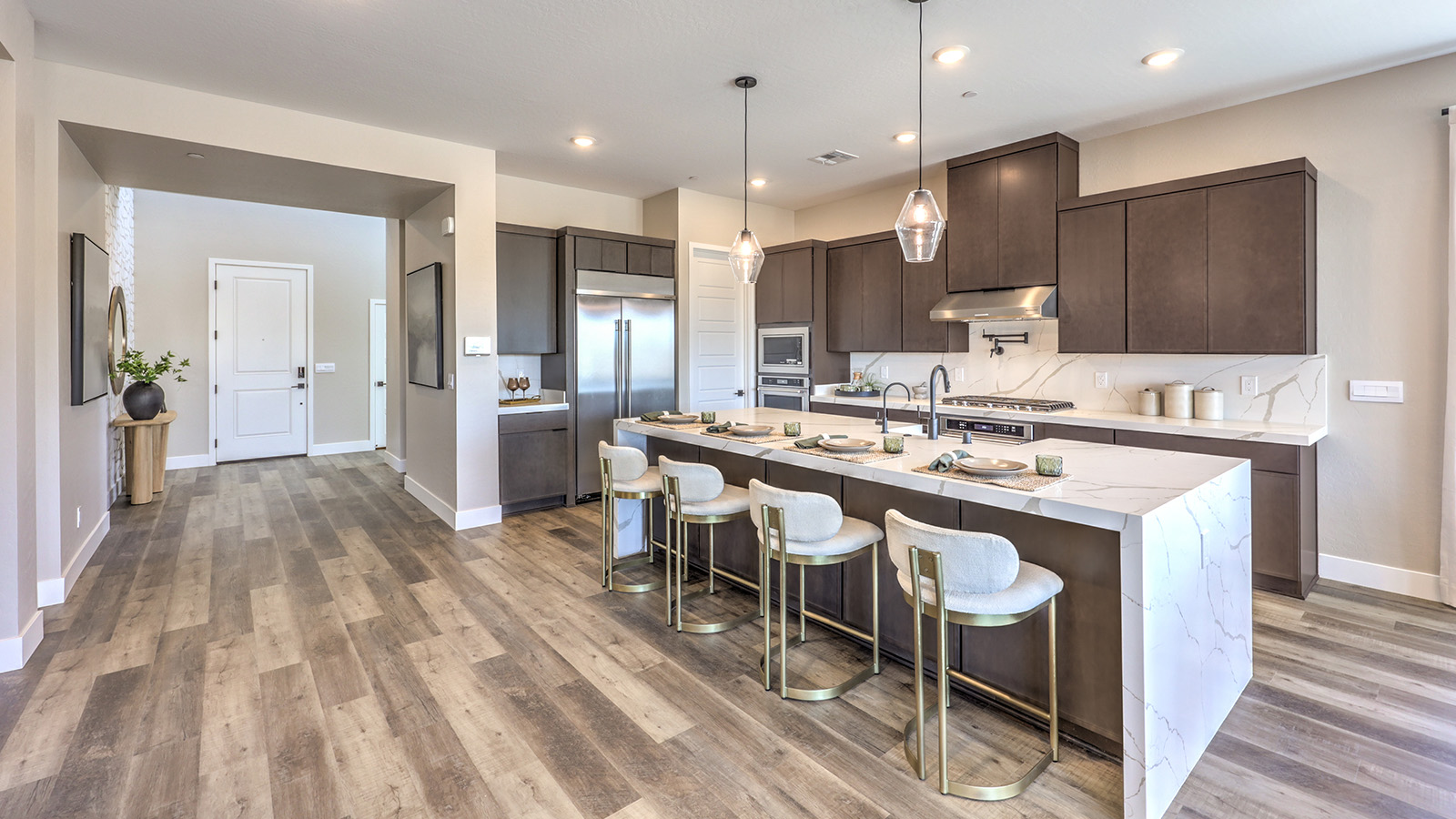 Our 4418 model kitchen in the Heartland Summit Community with brown shaker style cabinets, quartz countertops, a kitchen island, 5-burner cooktop, large pantry, and Whirlpool Stainless Steel appliances.
