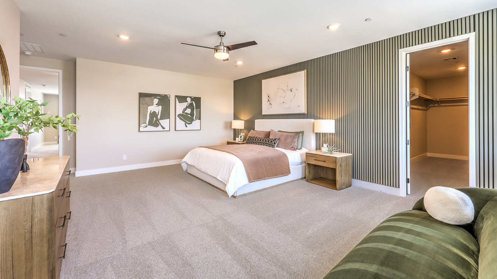 The Bedroom One Suite in our Heartland Summit 4418 model with carpet flooring, large windows, and a ceiling fan with a light kit.