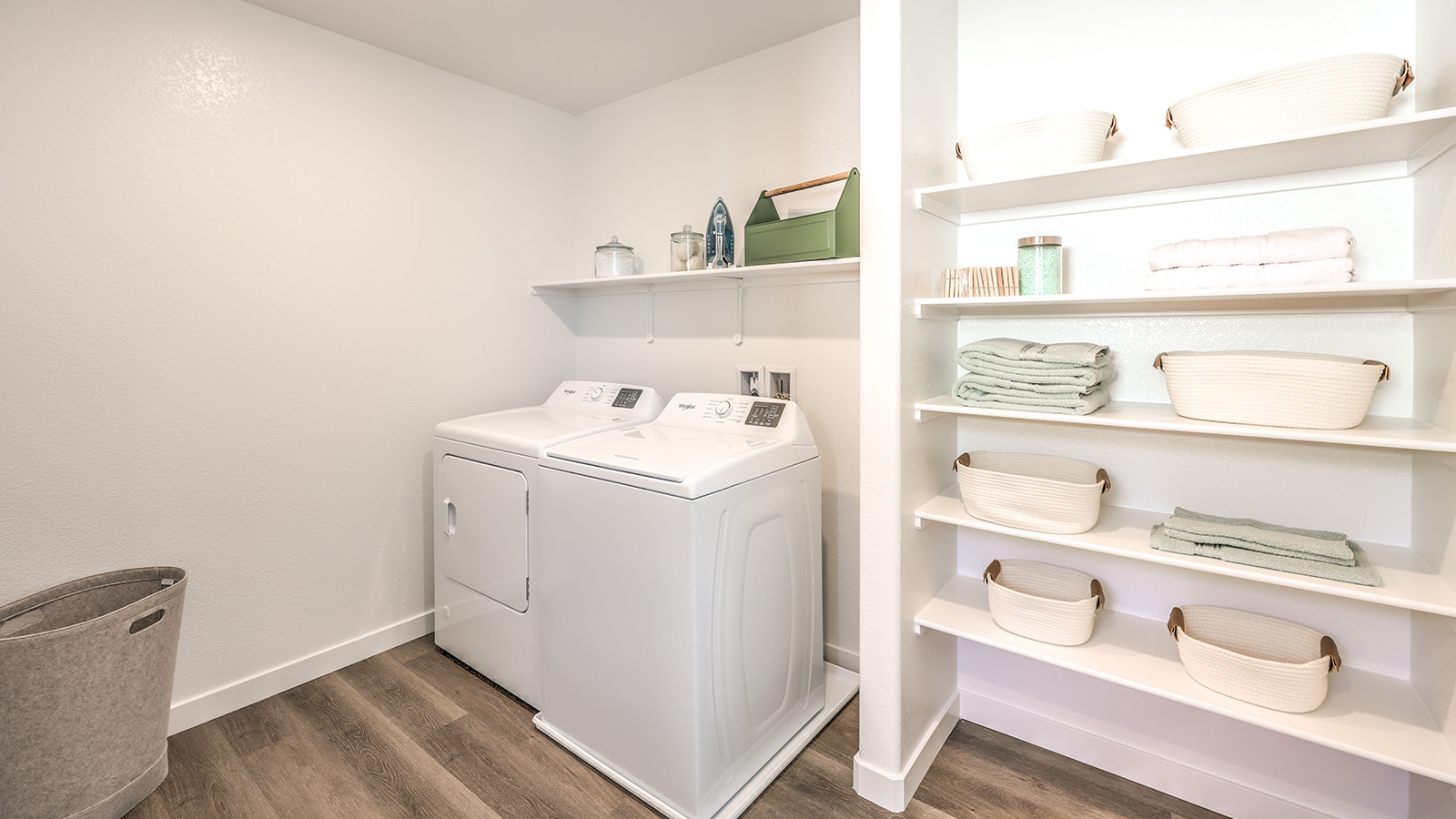 Our Heartland Bay 1802 model laundry room with shelves and a washer and dryer.