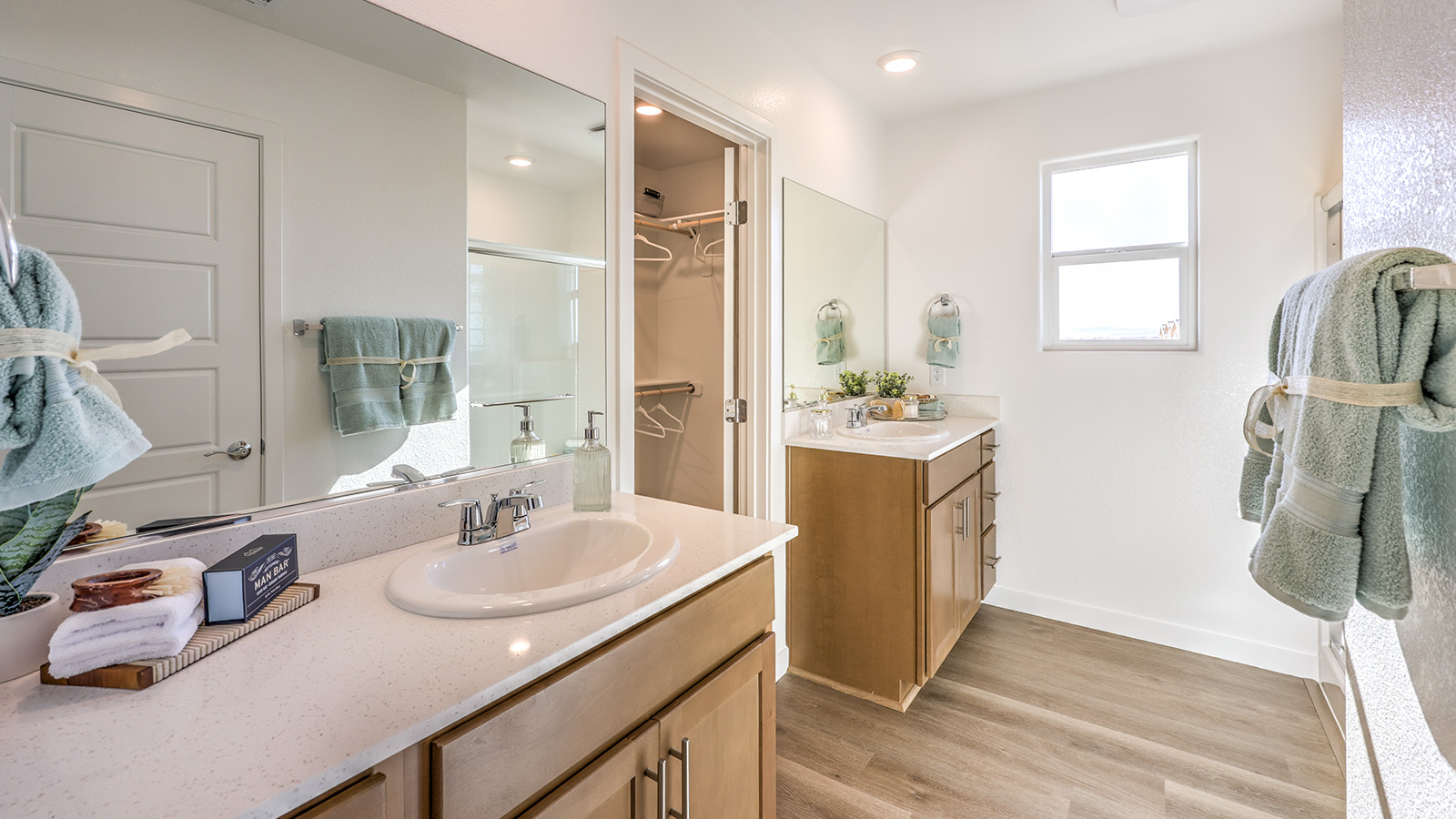 Attached to the Bedroom One Suite, our 1802 model bathroom with granite countertops at the double Bath Vanity, a walk-in shower, walk-in closet, mirror, and brown cabinets.