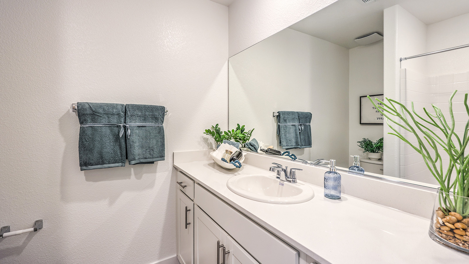 Bathroom Two in our Heartland Bay 1872 model with granite countertops at the Bath Vanity, a walk-in shower, mirror, and white cabinets.