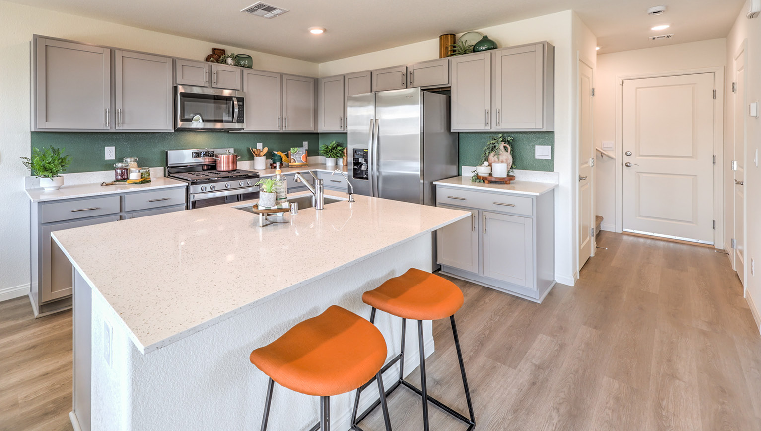 Our 1865 model kitchen in the Heartland Bay Community with grey shaker style cabinets, granite slab countertops, a kitchen island, large pantry, and Whirlpool Stainless Steel appliances.