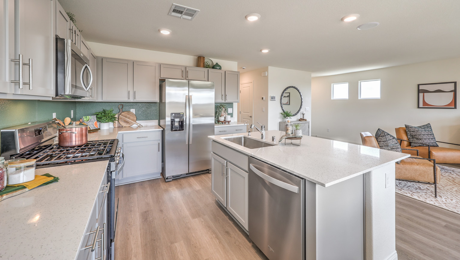 Our 1865 model kitchen in the Heartland Bay Community with grey shaker style cabinets, granite slab countertops, a kitchen island, large pantry, and Whirlpool Stainless Steel appliances.