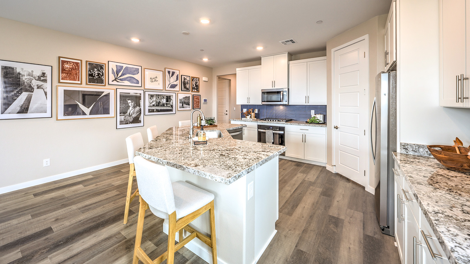 Our 1839 model kitchen in the Heartland Grove Community with white shaker style cabinets, quartz countertops, a kitchen island, large pantry, and Whirlpool Stainless Steel appliances.