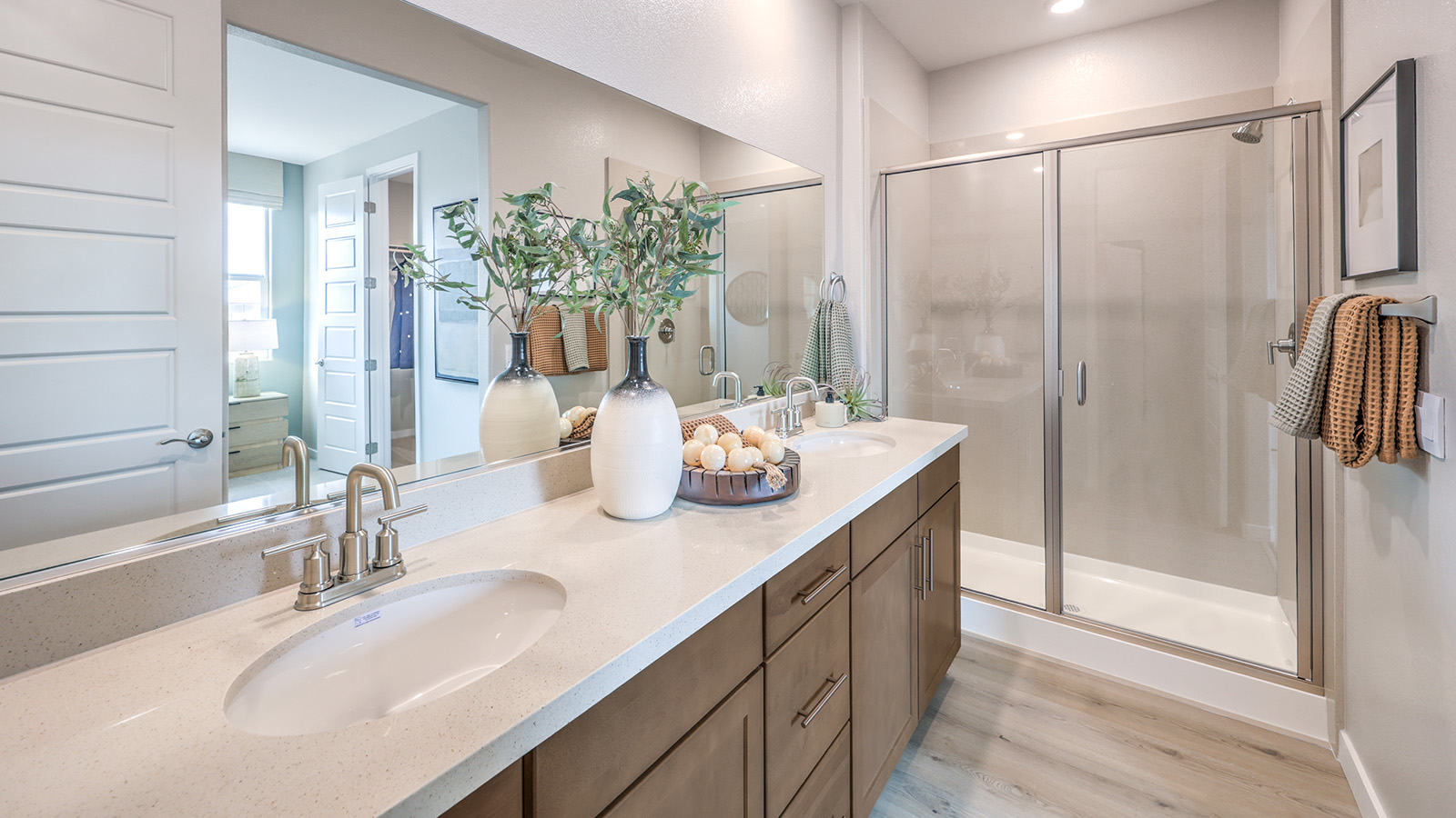 Attached to the Bedroom One Suite, our 2048 model bathroom with quartz/marble fusion countertops at the double Bath Vanity, a walk-in shower, walk-in closet, mirror, and grey cabinets.
