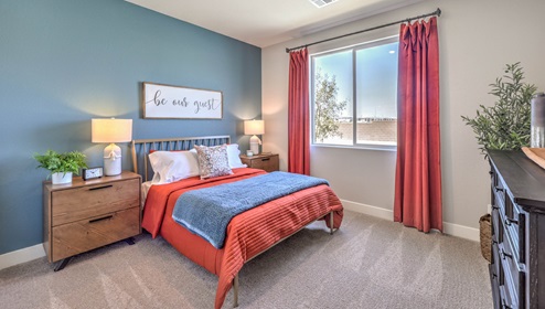 The second bedroom in our Heartland Manor 2754 Plan features plush carpet flooring, a spacious layout, and a large window that fills the room with natural light. The room offers a comfortable and inviting space, perfect for guests or family members.