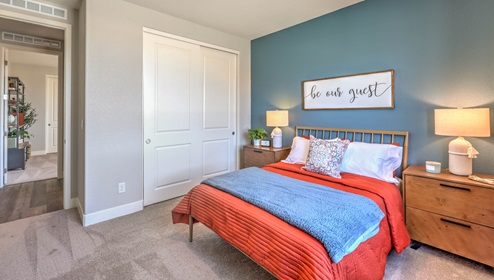 The second bedroom in our Heartland Manor 2754 Plan features plush carpet flooring, a spacious layout, and a large window that fills the room with natural light. The room offers a comfortable and inviting space, perfect for guests or family members.