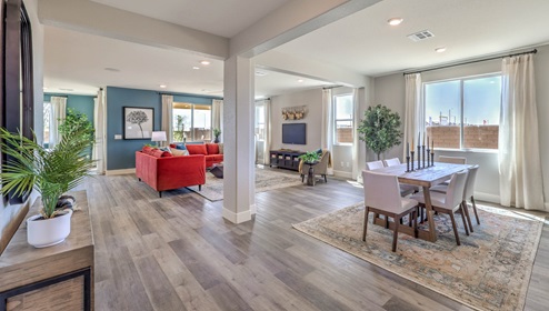 The dining room and great room in our Heartlnad Manor 2754 Plan features an open-concept design with 9-foot flat ceilings and luxury vinyl plank flooring. The dining area is spacious, with a large window allowing natural light to fill the space. Adjacent to it, the great room offers a bright and airy feel, enhanced by additional windows and sliding glass doors leading to the backyard. The seamless flow between these areas creates a welcoming and functional living space.