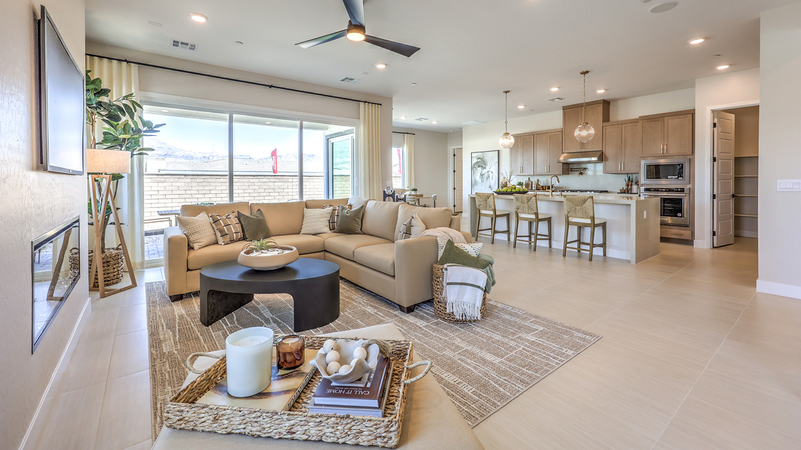 The great room in our Heartland Manor 2754 Plan features luxury vinyl plank flooring, an open-concept layout, and large windows that bring in natural light. The space flows seamlessly into the kitchen, creating a connected and spacious living area. A ceiling fan is centrally located, and sliding glass doors provide easy access to the backyard.