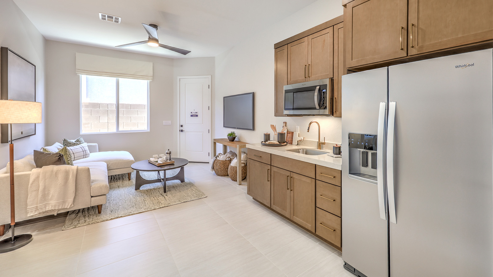 The kitchenette in the MultiGEN suite of our Heartland Manor 2754 Plan features luxury vinyl plank flooring, quartz or granite countertops, and ample cabinet storage. A stainless steel refrigerator and a built-in sink add convenience, creating a functional space for independent living. Designed for multi-generational flexibility, this kitchenette provides both comfort and practicality.