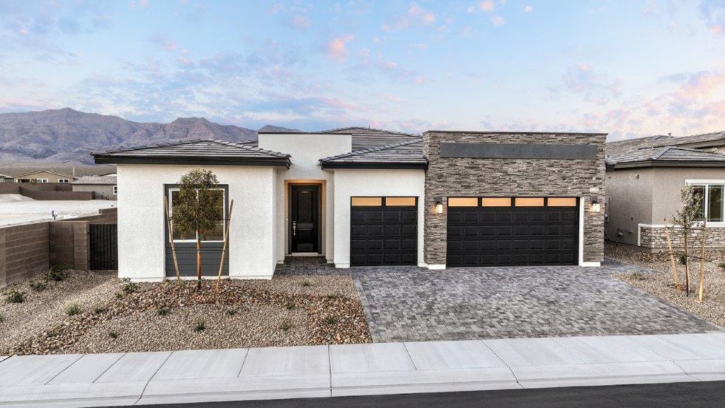 Our 2754 model home in the Heartland Manor community with white and black exterior paint schemes, a flat tile roof, front yard landscaping, paver walkways, and a three-car garage.