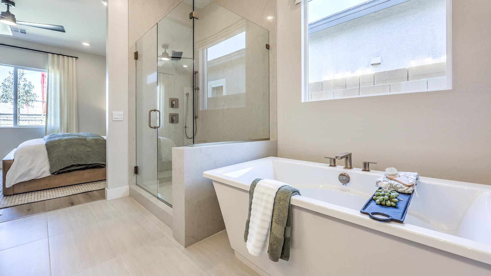 The main bathroom in our Heartland Manor 2754 Plan features luxury vinyl plank flooring, a spacious vanity with quartz or granite countertops, and dual sinks. A large mirror enhances the open feel of the space, while a window provides natural light. The bathroom connects to the main bedroom, offering both style and functionality.
