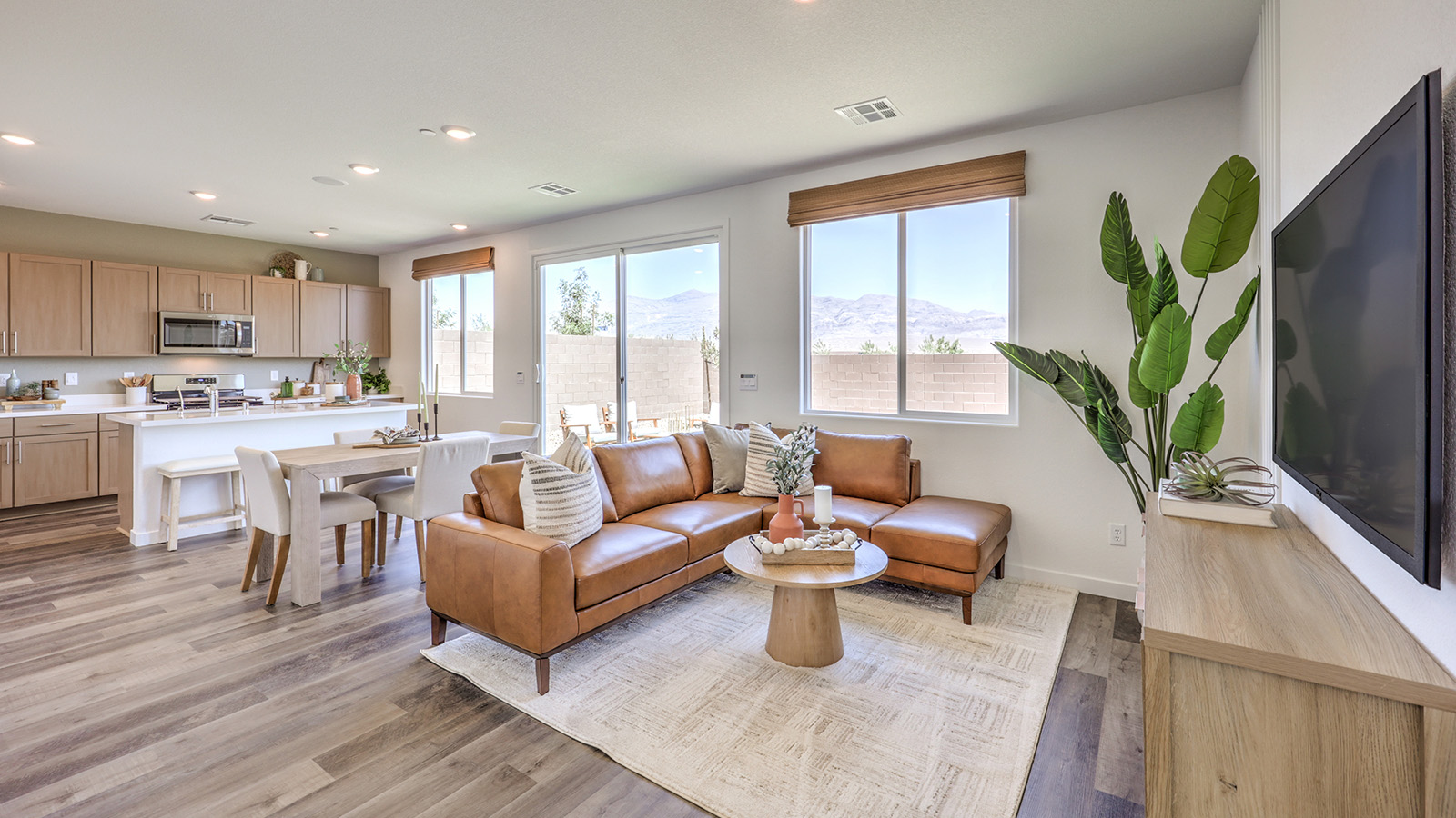 The Heartland Cottages 1700 Plan open concept Great Room with LVP panel flooring, two large windows, and a sliding door to the backyard.
