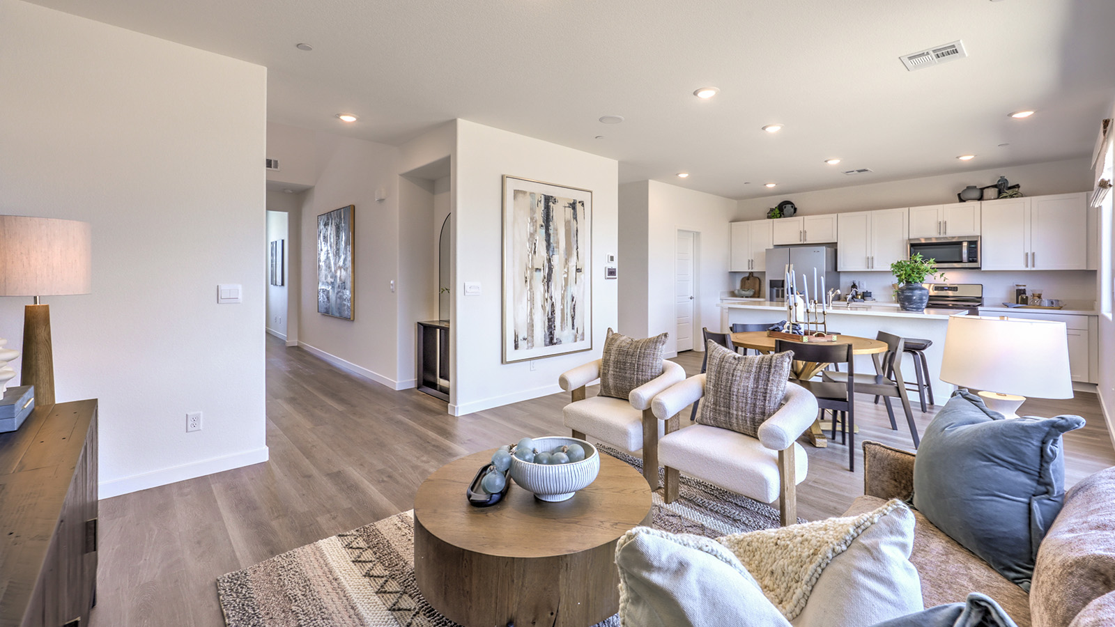 The Heartland Cottages 1865 Plan open concept Great Room with LVP panel flooring, two large windows, and a sliding door to the backyard.