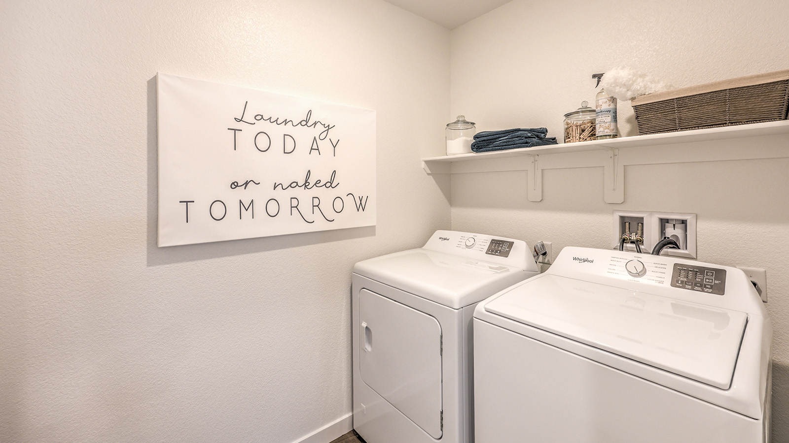 Our Heartland Cottage 1865 model laundry room with shelves and a washer and dryer.