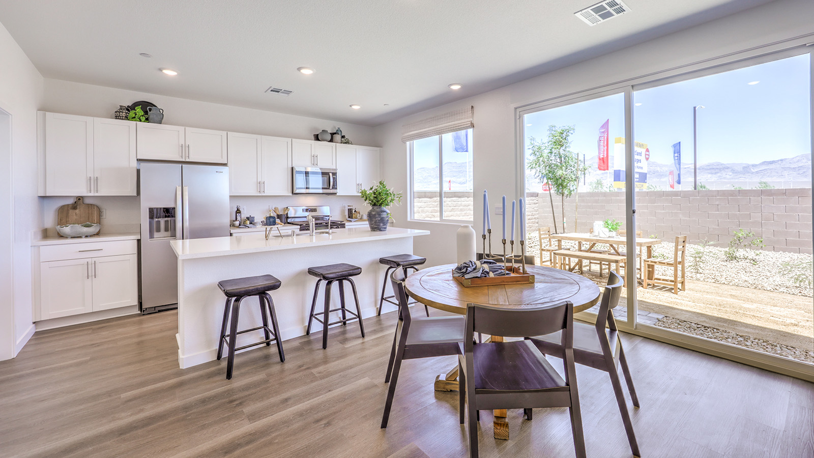 Our 1865 model kitchen in the Heartland Cottages Community with white shaker style cabinets, Granite Slab countertops, a kitchen island, and Whirlpool Stainless Steel appliances.