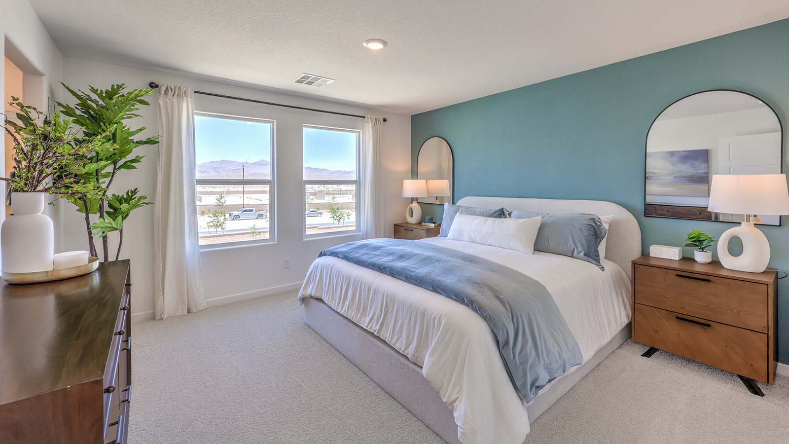The Bedroom One Suite in our Heartland Cottages 1865 model with carpet flooring, walk-in closet, and a ceiling fan with a light kit.