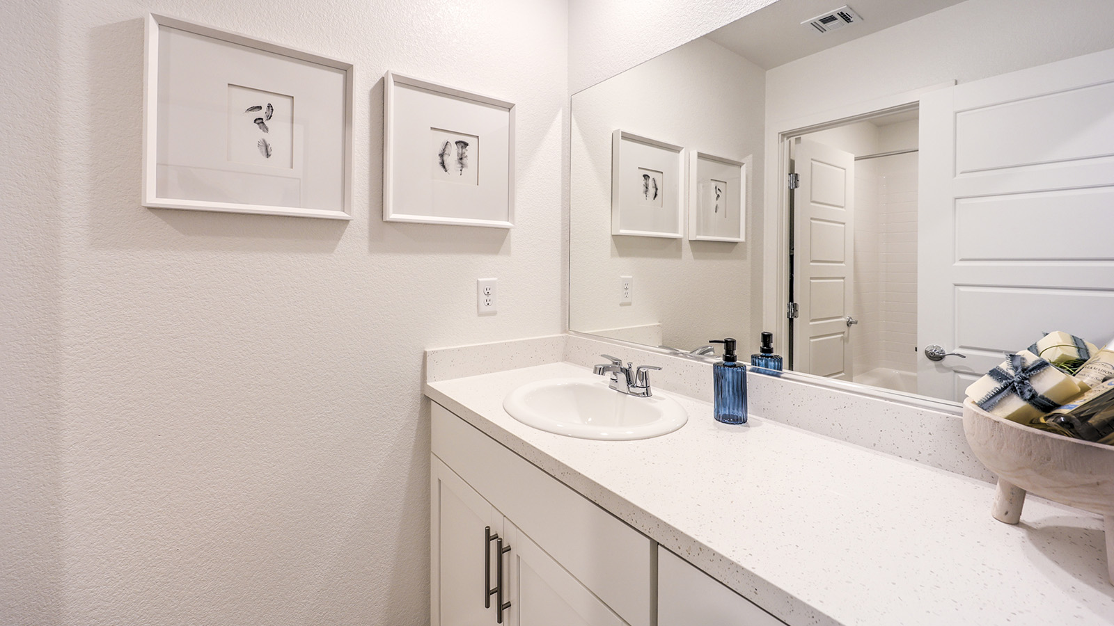 Bathroom Two in our Heartland Cottage 1865 model with granite countertops at the Bath Vanity, a walk-in shower, mirror, and white cabinets.