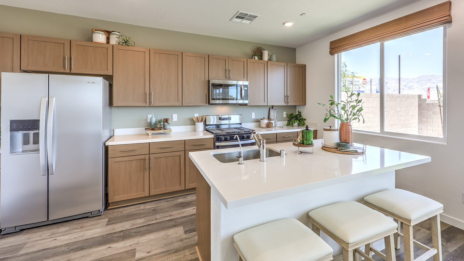 Our 1700 model kitchen in the Heartland Cottages Community with white shaker style cabinets, Granite Slab countertops, a kitchen island, and Whirlpool Stainless Steel appliances.