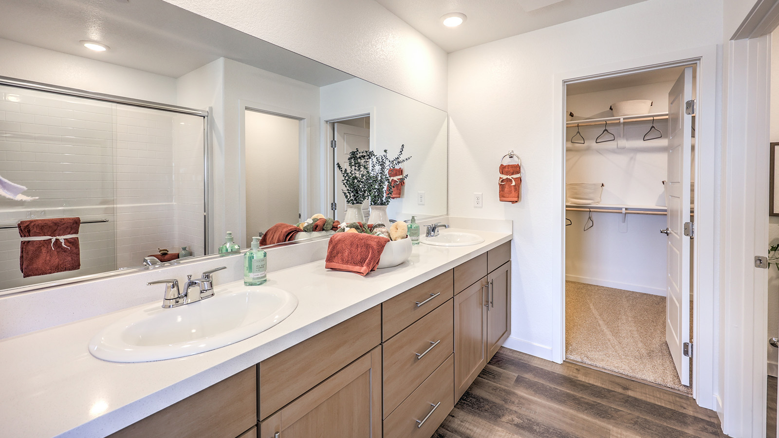 Attached to the Bedroom One Suite, our 1700 model bathroom with granite countertops at the double Bath Vanity, a walk-in shower, mirror, and white cabinets.