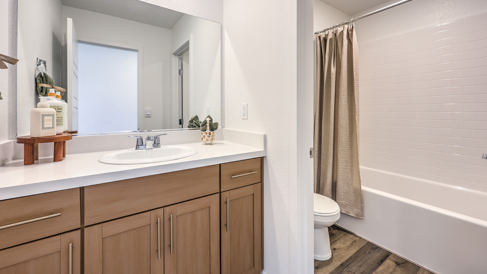 Bathroom Two in our Heartland Cottage 1700 model with granite countertops at the Bath Vanity, a walk-in shower, mirror, and white cabinets.