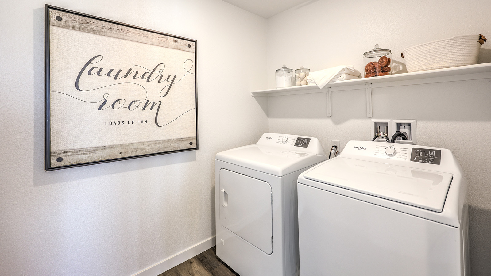 Our Heartland Cottage 1700 model laundry room with shelves and a washer and dryer.