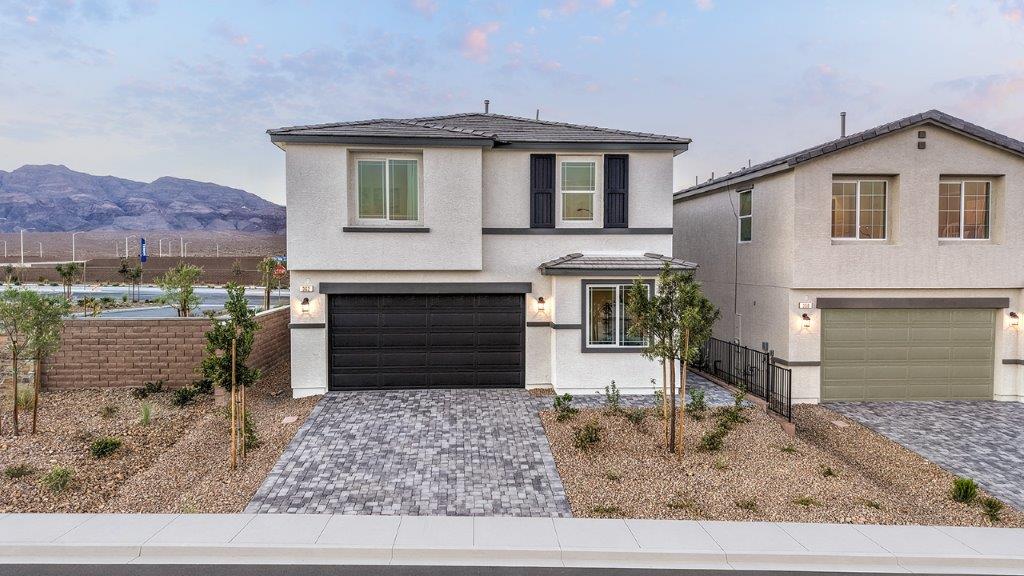 Our 1865 model home in the Heartland Cottages community with white and black exterior paint schemes, a flat tile roof, front yard landscaping, and paver walkways.