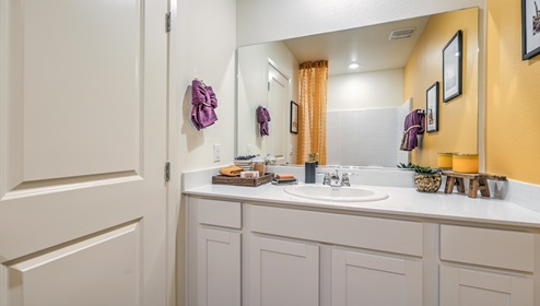 Bathroom Two in our Canyon Trails 1309 model with quartz/marble fusion countertops at the Bath Vanity, a walk-in shower, mirror, and white cabinets.