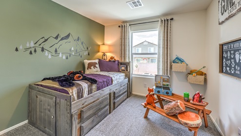 The Office/Bedroom Two option in our Canyon Trails 1309 model with carpet flooring and a sliding closet, furnished with a bed and play area for a young child.