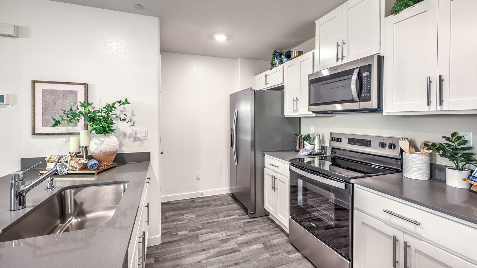 Our 1309 model kitchen in the Canyon Trails  Community with white shaker style style cabinets, quartz countertops, and Whirlpool Stainless Steel appliances.
