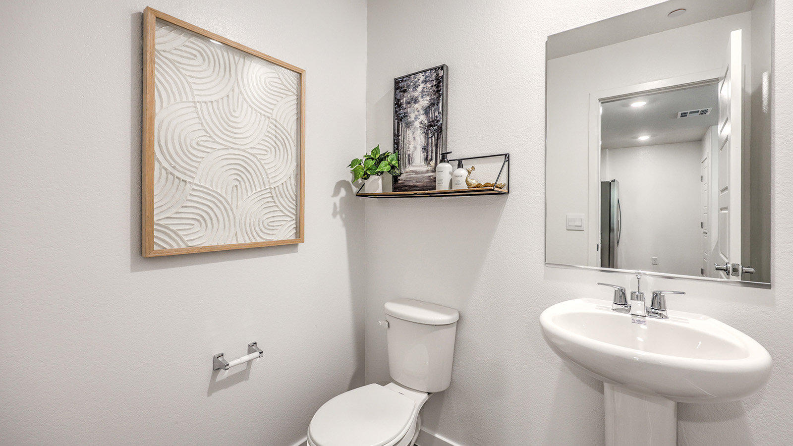 The powder bathroom in our Canyon Trails 1309 model with a pedestal sink, mirror, and toilet.