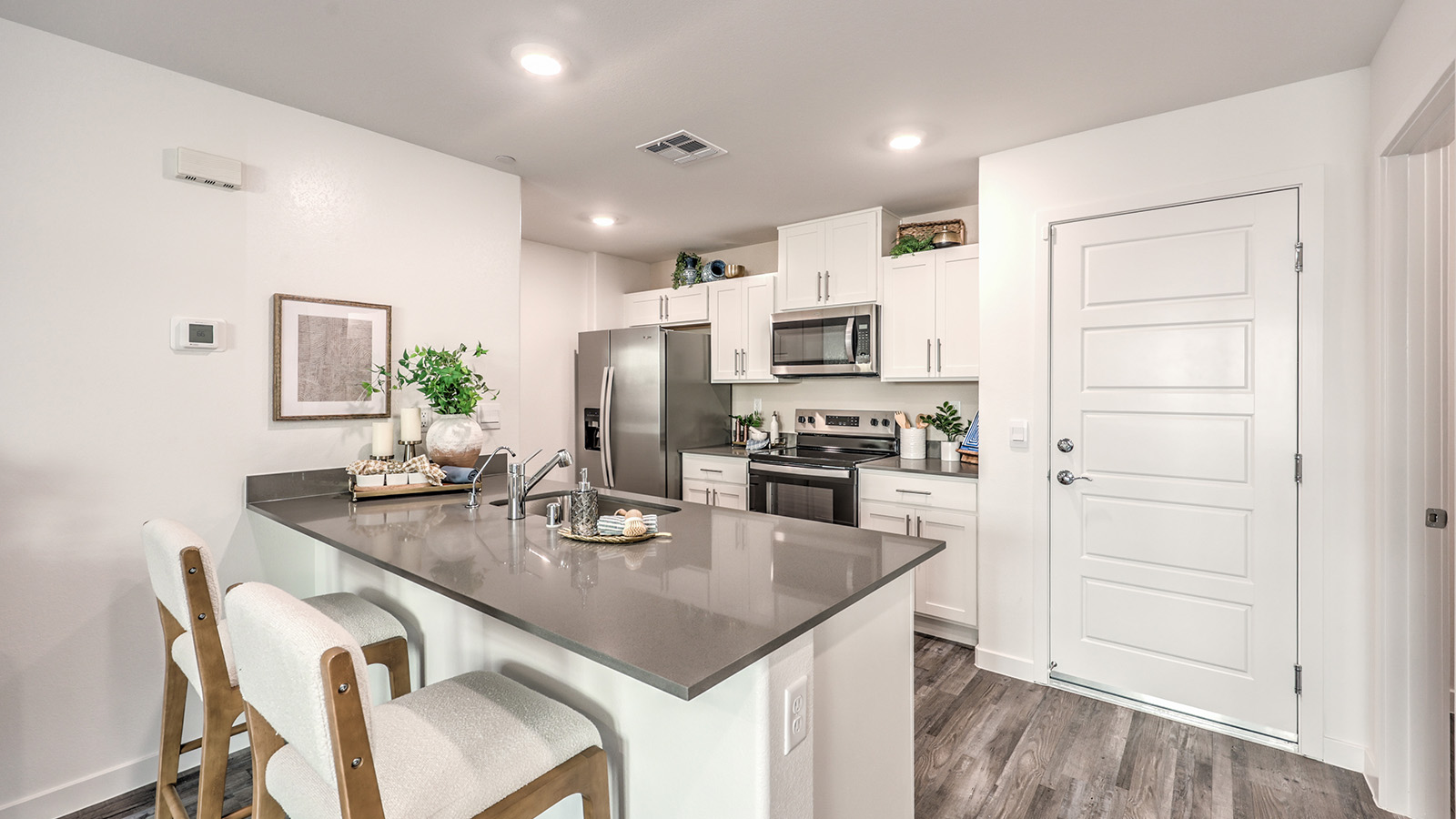 Our 1309 model kitchen in the Canyon Trails  Community with white shaker style style cabinets, quartz countertops, and Whirlpool Stainless Steel appliances.