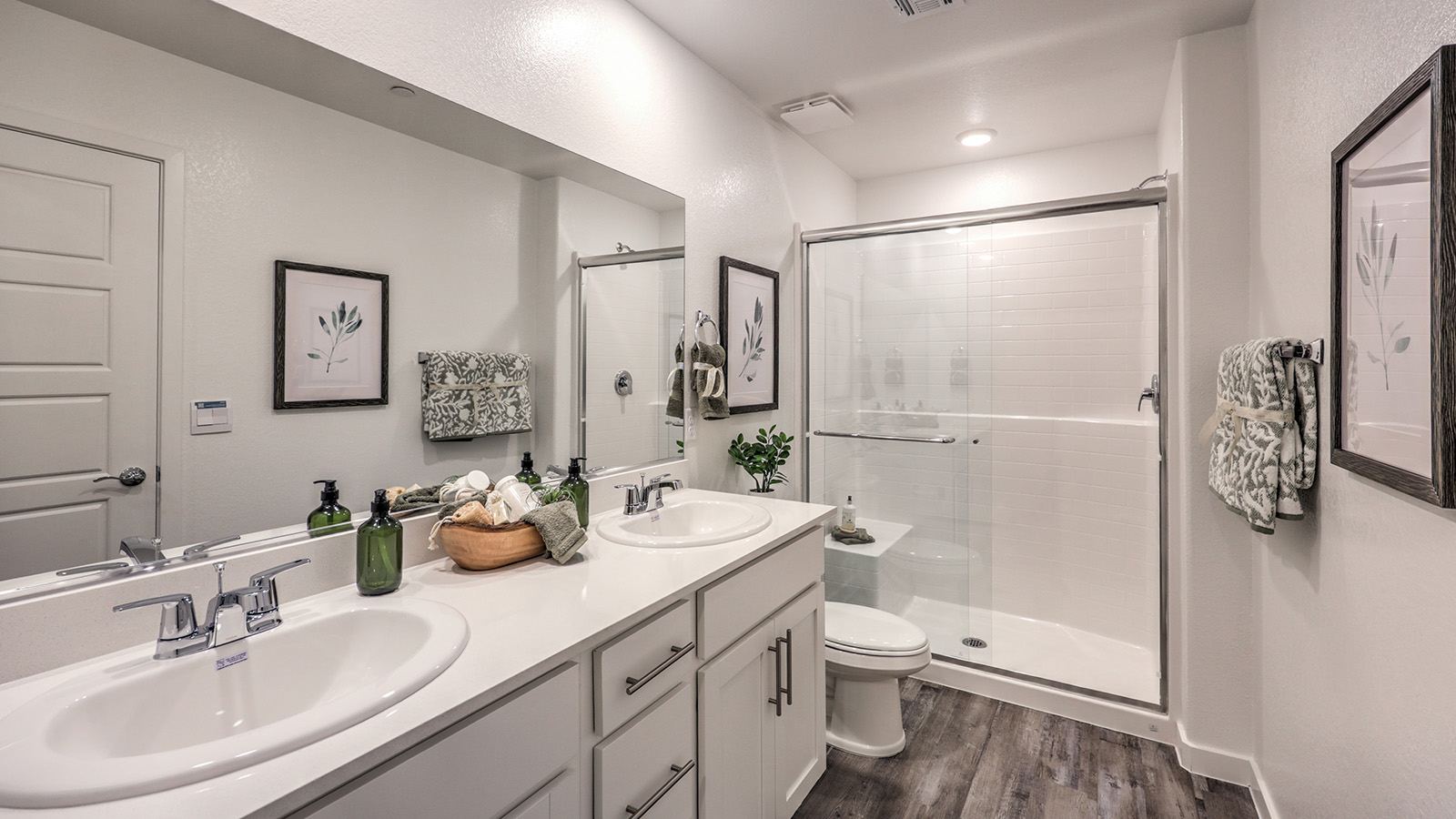 Attached to the Bedroom One Suite, our 1410 model bathroom with quartz/marble fusion countertops at the Bath Vanity, a walk-in closet, mirror, and white cabinets.