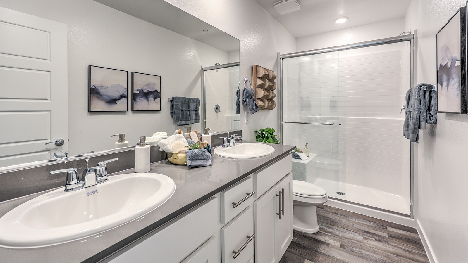 Attached to the Bedroom One Suite, our 1309 model bathroom with quartz/marble fusion countertops at the Bath Vanity, a walk-in shower, mirror, and white cabinets.