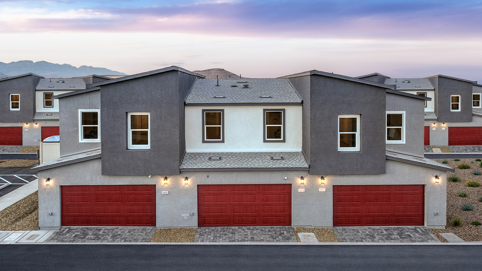 Our 1309 model home in the Canyon Trails community with red exterior paint schemes, common area landscaping, and paved walkways.