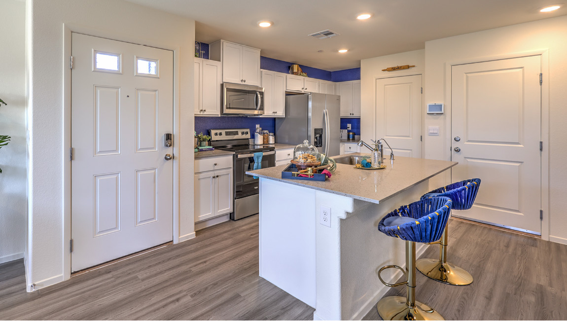 Our 1430 model kitchen in the Kalea Trails Community with white shaker style cabinets, quartz countertops, a kitchen island, and Whirlpool Stainless Steel appliances.