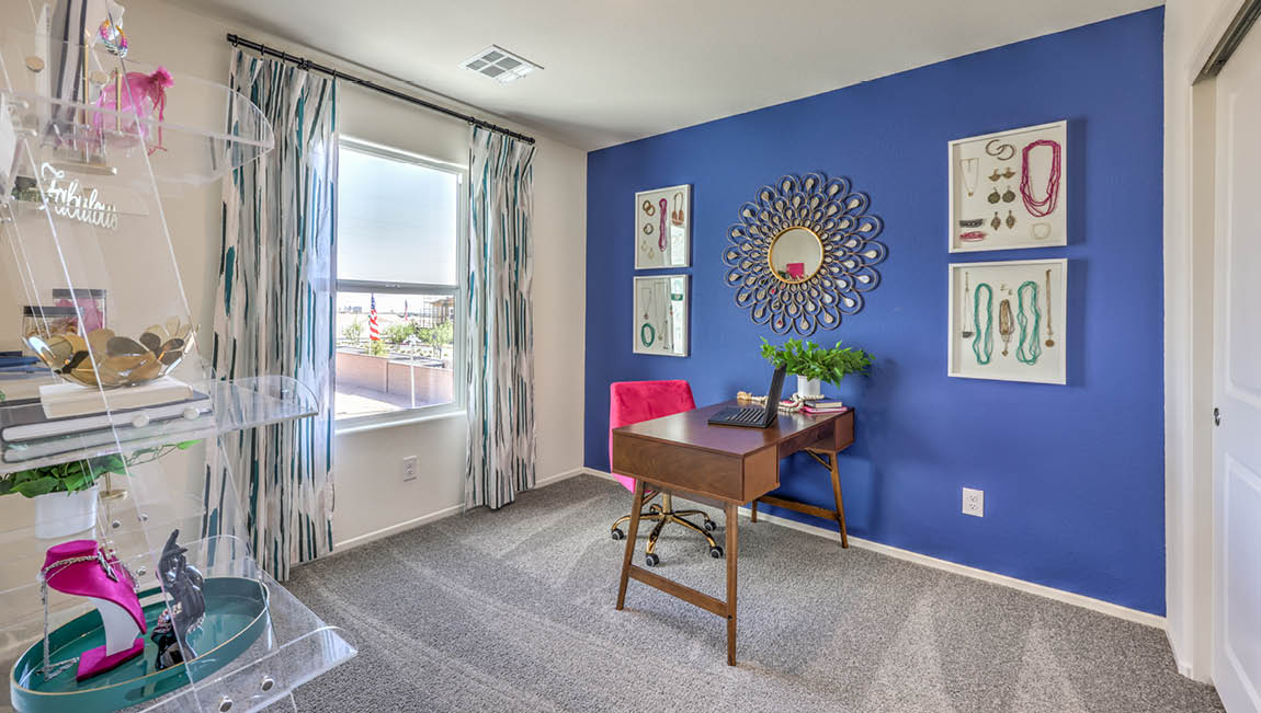 The Office/Bedroom Two option in our Kalea Trails 1430 model with carpet flooring, a sliding closet, and a window, furnished with a desk and chair.