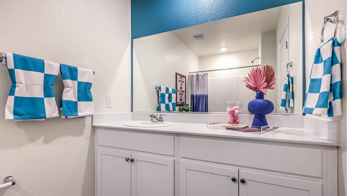 Bathroom Two in our Kalea Trails 1430 model with quartz countertops at the Bath Vanity, a walk-in shower, mirror, and white cabinets.