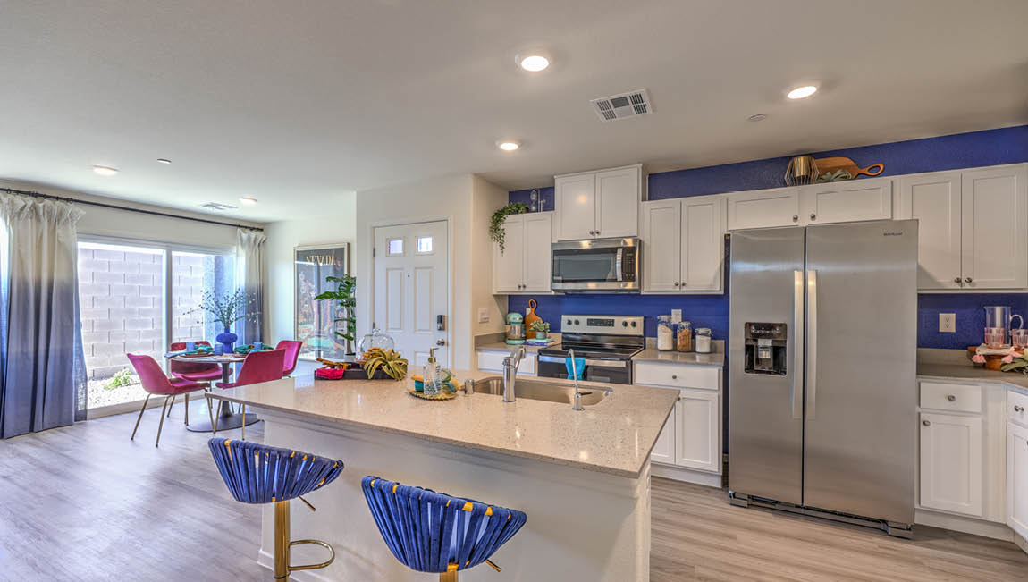 Our 1430 model kitchen in the Kalea Trails Community with white shaker style cabinets, quartz countertops, a kitchen island, and Whirlpool Stainless Steel appliances.